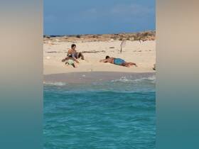 A group of friends enjoys a relaxing day on the beach, soaking up the sun and enjoying the serene surroundings — perfect for a tropical getaway.
