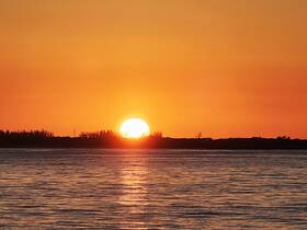 A stunning sunset over calm waters, creating a picturesque backdrop perfect for evening boat cruises.