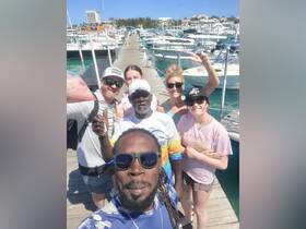 A cheerful group poses for a selfie at the marina, capturing a fun moment before their boating adventure. Perfect for showcasing group outings and memorable experiences on the water.