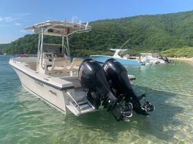 A Mako boat is docked in clear waters, showcasing its sleek design against a lush green backdrop, perfect for a day of adventure on the water.