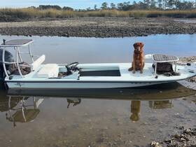 A golden retriever sits proudly on the deck of a fishing boat, showcasing the vessel's sleek design against a serene natural backdrop.