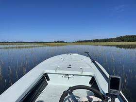 A serene view from the front of a boat navigating through calm waters surrounded by lush marsh grass, perfect for exploring nature and fishing.