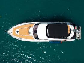 Aerial view of a sleek yacht cruising through clear turquoise waters, showcasing its elegant design and spacious deck.
