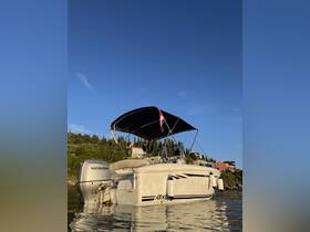 A sleek speedboat named 'ARKO' is docked, showcasing its stylish design against a clear blue sky and lush green hills in the background.