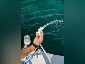 A hand operates a water hose on a boat, showcasing essential equipment for onboard convenience and maintenance.