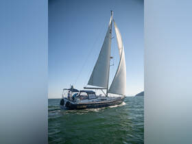 A beautiful sailboat, 'Quella Bella', glides through the water with a group of guests enjoying the sailing experience under clear skies.