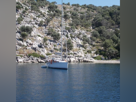 A serene view of a sailboat anchored near rocky shores, showcasing the beauty of coastal landscapes and ideal for sailing enthusiasts.