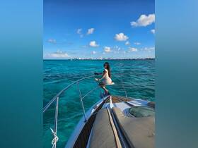 A woman enjoys the stunning ocean view while perched on the bow of a boat, capturing the essence of a perfect day on the water.