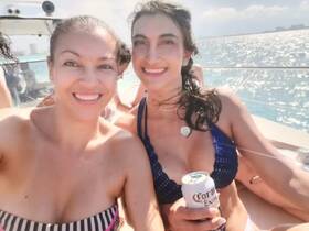 Two friends enjoy a sunny boat party, smiling and sipping drinks, capturing the essence of fun and relaxation on the water.