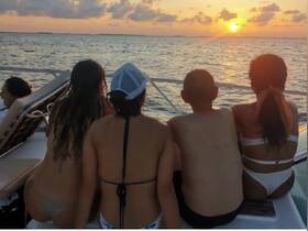 A group enjoys a stunning sunset from the deck of a boat, creating a perfect backdrop for memorable moments and celebrations on the water.