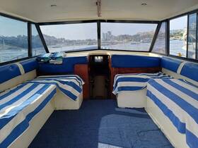 Interior view of a boat cabin featuring comfortable seating with blue and white striped covers, perfect for relaxing while enjoying the scenic views outside.