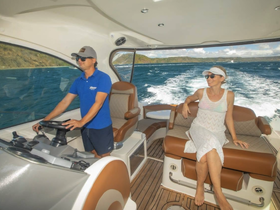 A couple enjoys the comfort of the helm area on a boat, with one steering and the other relaxing — perfect for a day out on the water.