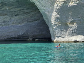 A mother and child enjoy kayaking in the stunning turquoise waters beneath a majestic cave, showcasing a perfect family adventure in nature.