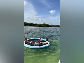 A joyful family enjoys splashing around in a floating pool in the water, creating memorable moments under the sun.
