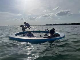 A joyful family enjoys a fun day in the water, playing and relaxing on a floating mat — perfect for summer adventures and family bonding.
