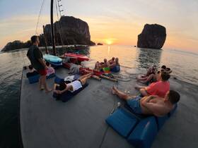 A lively group enjoys a stunning sunset aboard a yacht, lounging on comfortable seating while sipping drinks — the perfect setting for relaxation and celebration.