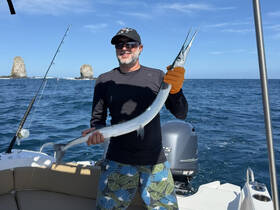 A man proudly displays his catch while fishing on a boat in the ocean, showcasing the thrill of a successful day on the water.