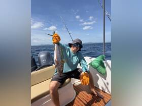 A proud angler displays his catch aboard a fishing boat, showcasing the thrill of deep-sea fishing in open waters.