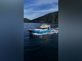 A vibrant boat cruises through serene waters with lush mountains in the background, showcasing an ideal day on the water.