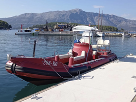 A vibrant red speedboat docked at a marina, surrounded by scenic mountains and clear waters, perfect for exploring coastal destinations.
