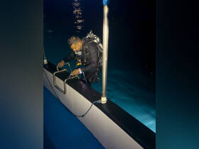 A diver prepares to enter the water from a boat at night, showcasing the thrilling experience of night diving in serene waters.