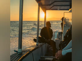 Two individuals enjoy a serene sunset on a boat, capturing the essence of a peaceful evening at sea.