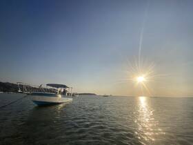 A serene view of a boat anchored in shallow waters during sunset, showcasing the tranquil beauty of a coastal evening.