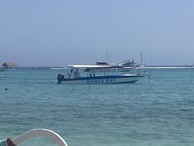 A clear view of the 'MANTA RAY' boat anchored in tranquil waters, showcasing the vessel's structure against a serene backdrop.