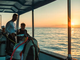 A joyful group prepares for a diving adventure at sunset, showcasing the excitement of underwater exploration on a beautiful evening.