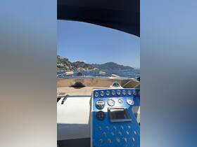 A view of the helm and console from inside a boat, showcasing the controls and a glimpse of the scenic coastline in the background.