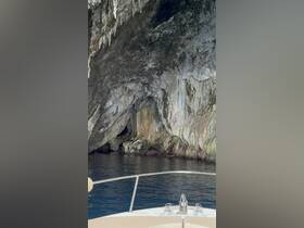 A stunning view of a rocky cave along the coastline, captured from the bow of a boat, showcasing the natural beauty of the area.