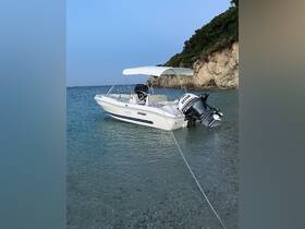 A sleek speedboat anchored in crystal-clear waters, showcasing its elegant design against a scenic backdrop of rocky cliffs.