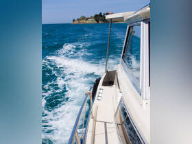 A side view of a boat cruising through vibrant blue waters, showcasing the vessel's sleek design and the scenic coastline in the background.