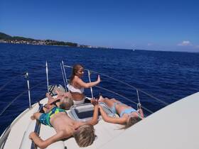 A group of children enjoys a sunny day on the boat, relaxing and sunbathing while taking in the beautiful ocean views — perfect for family outings and summer adventures.