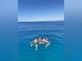 A joyful group of four enjoys swimming in the crystal-clear ocean, creating unforgettable memories on their boating adventure.
