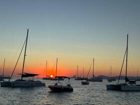A serene sunset view featuring multiple sailboats anchored in calm waters, creating a picturesque scene perfect for evening relaxation.