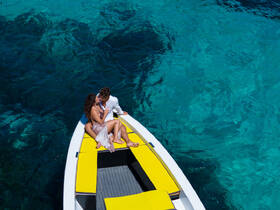 A romantic moment captured as a couple shares a kiss on a boat, surrounded by stunning clear waters — perfect for lovebirds seeking unforgettable experiences on the water.