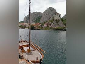 A beautifully crafted wooden boat docked in a serene harbor, surrounded by stunning rocky cliffs and quaint buildings, perfect for exploring coastal destinations.