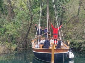 A lively group celebrates aboard a traditional boat surrounded by lush greenery, showcasing the joy of exploring nature on the water.