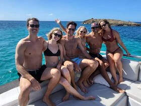 A cheerful group of friends enjoys a sunny day on a boat, capturing the essence of fun and camaraderie on the water.