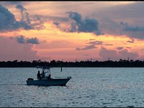 A serene sunset view featuring a boat cruising on calm waters, creating a picturesque backdrop for evening adventures.