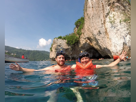 Two friends enjoy snorkeling in crystal-clear waters near a stunning cave, capturing the essence of adventure and fun in the great outdoors.