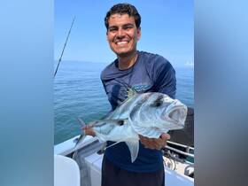 A joyful angler proudly displays his catch while fishing on a calm ocean, showcasing the thrill of a successful day on the water.