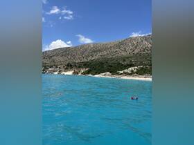 A stunning view of a turquoise coastline with lush hills in the background, perfect for showcasing the natural beauty of the area.