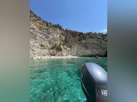 A stunning view of a rocky coastline with crystal-clear waters, where people enjoy a beach day. Perfect for showcasing beautiful summer destinations.
