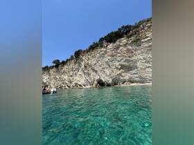 A stunning view of a rocky coastline with crystal-clear waters, showcasing the beauty of a perfect day on the water.