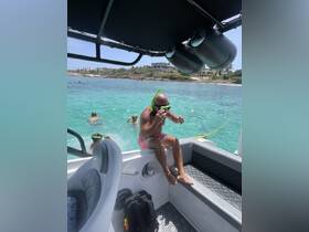 A lively scene of guests enjoying snorkeling in clear turquoise waters, with one person preparing to dive from the boat — a perfect day of aquatic adventure.