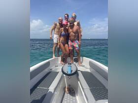 A lively group of friends poses on the bow of a boat, enjoying a sunny day on the water — perfect for summer adventures and celebrations.