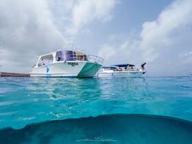 Two boats, MOKKA and SIMBA, are anchored in crystal-clear waters with guests enjoying the sun and activities — a perfect setting for a day of adventure on the water.