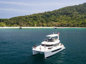 A stunning aerial view of a catamaran anchored near a lush green coastline, showcasing the beauty of tropical waters and perfect for island hopping adventures.